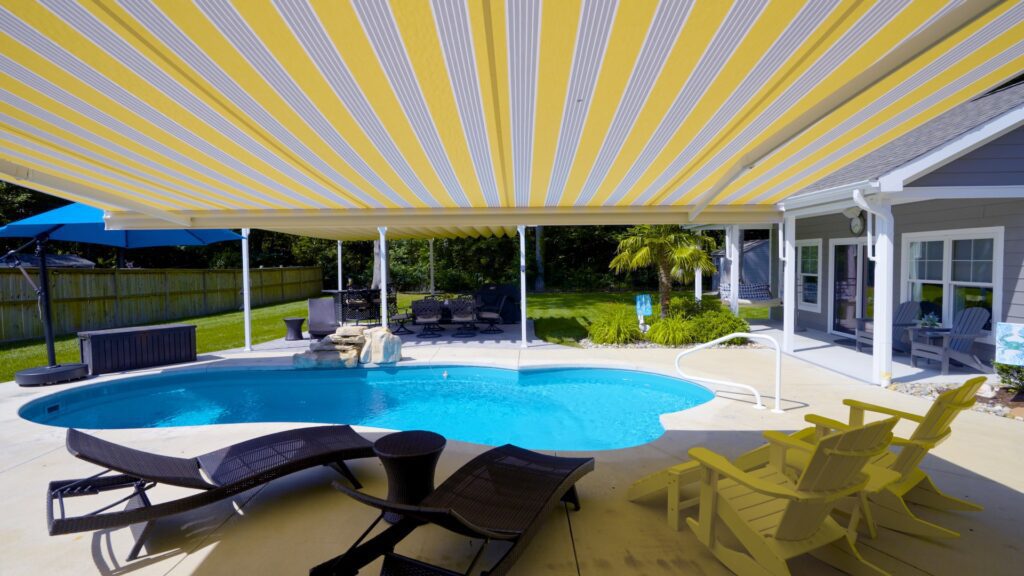 Lounge chairs by pool under a retractable motorized awning - ECCO Sunroom & Awning | Benefits of Retractable Awnings