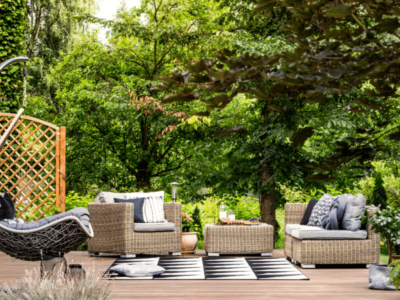 Deck with wicker furniture surrounded by plants | Stay Cool in Backyard